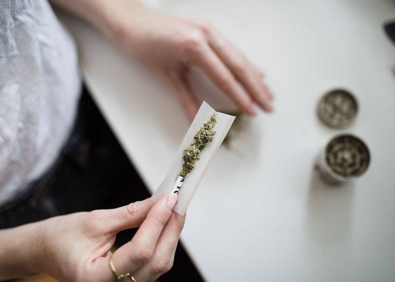hands rolling a joint of marijuana